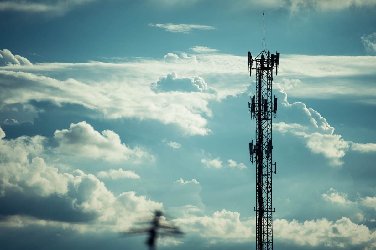 A tall communication tower silhouetted against a cloudy sky