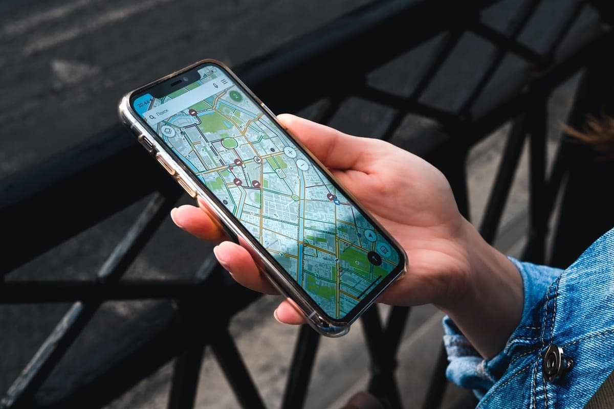 A hand holding a smartphone displaying a map app outdoors