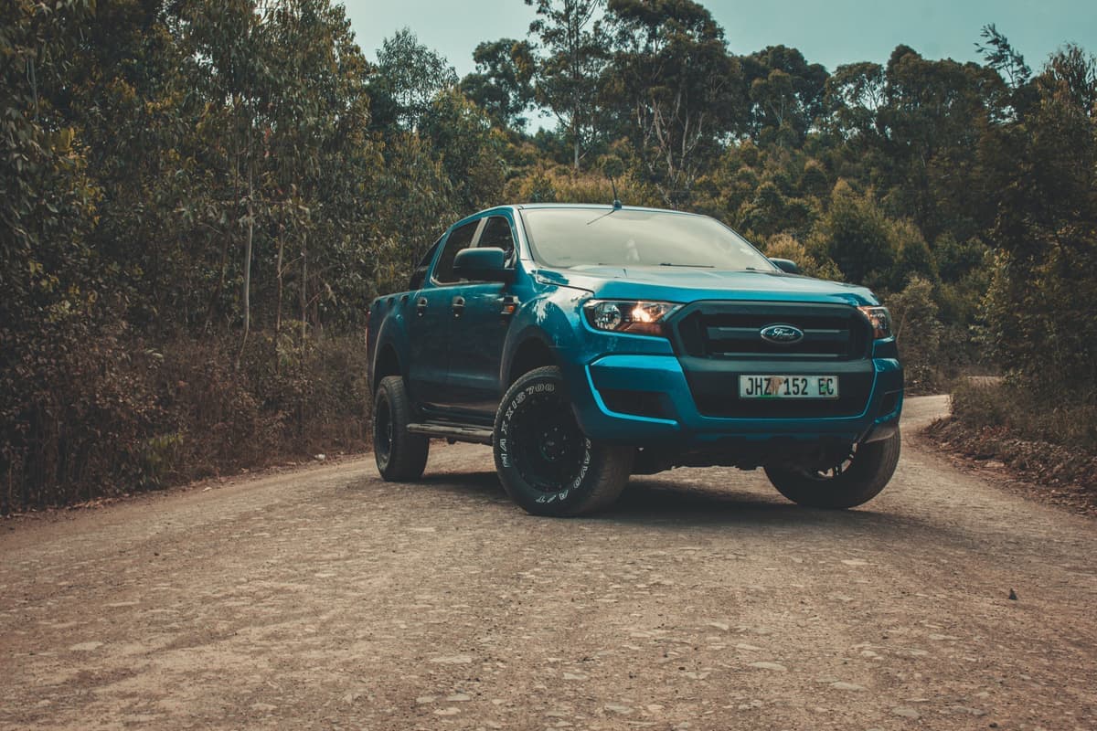 A pickup truck parked on a dirt road in the forest