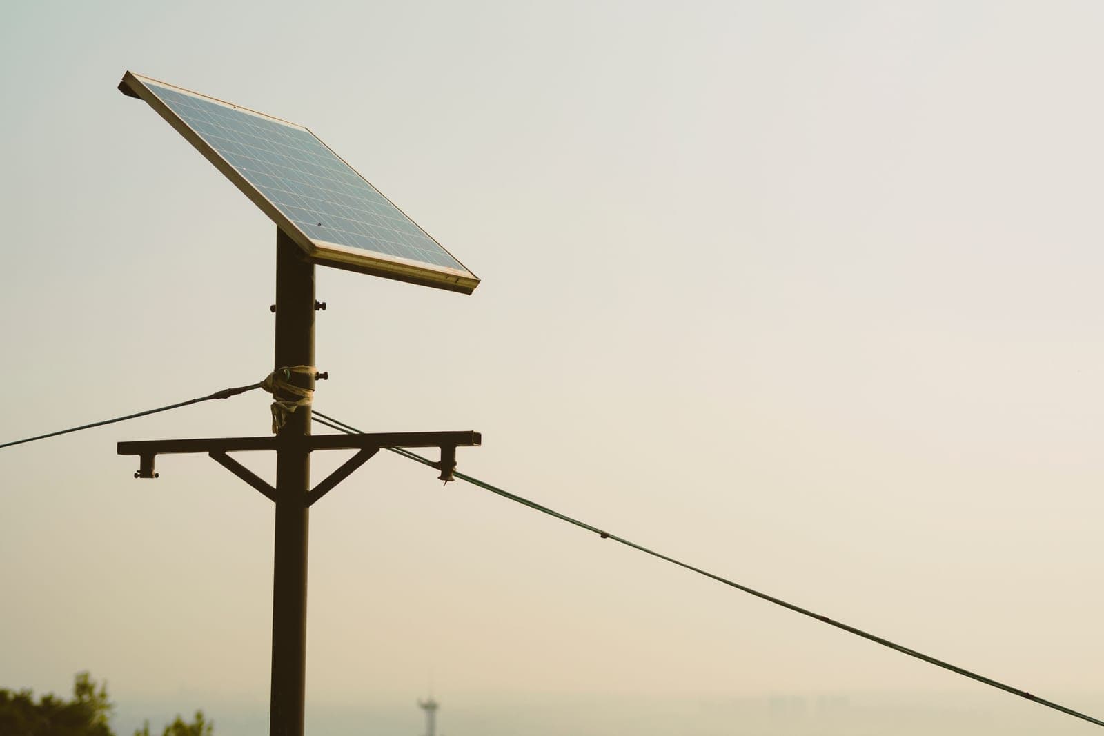 A single small solar panel mounted on a tall post against a clear sky